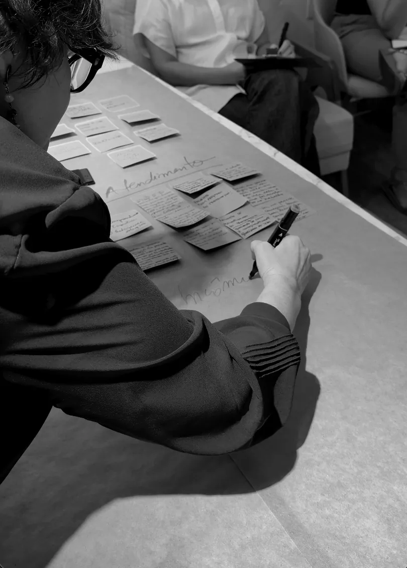 Dani Ramos escrevendo em post-its sobre a mesa durante um workshop