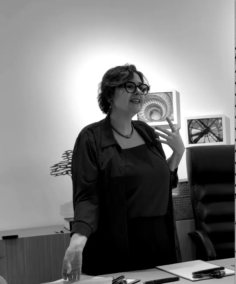 Dani Ramos de pé, explicando com as mãos durante um workshop na sala de um cliente